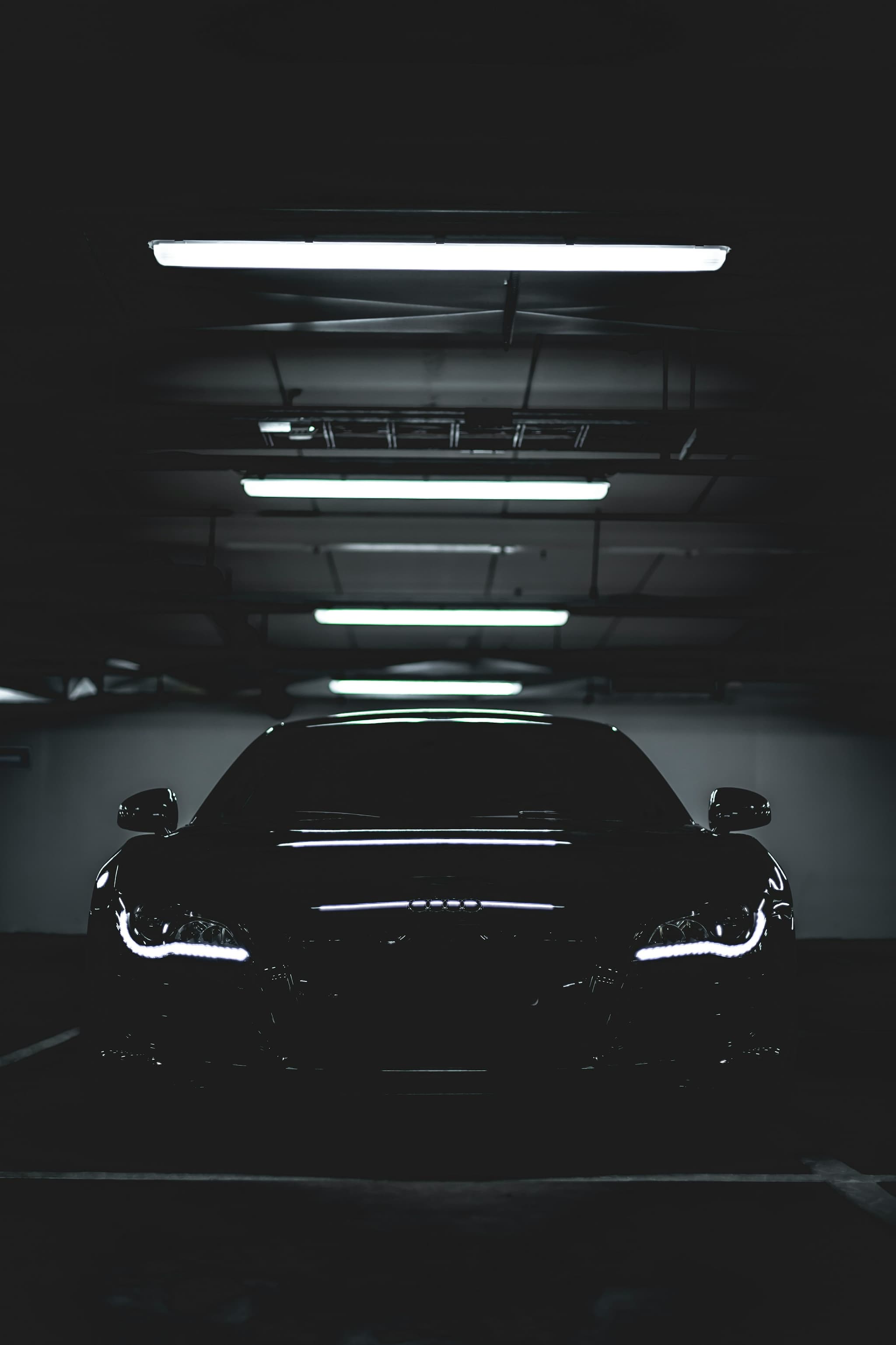 A black car under strip lighting in a darkened garage